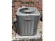 Close-up of a Lennox HVAC unit situated outside a brick wall, set on a stone base and surrounded by gravel at 9653 Woodsong Way, Indianapolis, IN 46229