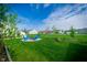 Lush backyard with manicured lawn, blue chairs around a firepit, and beautiful landscaping at 9804 Canyon Ln, Pendleton, IN 46064