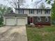 Two-story home with a two car garage, brick and vinyl siding, and a red front door at 10361 E 30Th St, Indianapolis, IN 46229