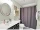 Cozy bathroom features an oval mirror, black and white vanity, and shower with gray curtain at 10882 Camden Ct, Fishers, IN 46038