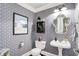 Stylish half bathroom featuring patterned wallpaper, decorative mirror, and pedestal sink at 10882 Camden Ct, Fishers, IN 46038