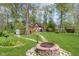 Landscaped backyard featuring a quaint wooden outbuilding, stone fire pit, and lush green lawn at 10935 Cornell St, Carmel, IN 46280