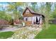 Exterior of wooden outbuilding featuring a quaint porch, patio seating, and stone pathway amid a lush lawn at 10935 Cornell St, Carmel, IN 46280