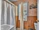 Bathroom featuring a shower, toilet, sink, window, and wood paneling at 1617 E Kelly St, Indianapolis, IN 46203