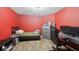 Red-walled bedroom featuring a bed, dresser, desk, and wood-look floors at 16264 Red Clover Ln, Noblesville, IN 46062