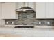 Kitchen with stone backsplash, stainless vent hood, granite countertop, and white cabinets at 16264 Red Clover Ln, Noblesville, IN 46062