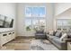 Bright living room with large windows, wood floors, and a comfortable gray sofa at 16264 Red Clover Ln, Noblesville, IN 46062
