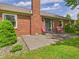 Brick home's back patio featuring sliding glass doors, outdoor chairs, and well-kept landscaping at 1645 Woodview Ln, Anderson, IN 46011