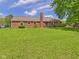 Spacious backyard with green lawn and brick house featuring a chimney and well-maintained landscaping at 1645 Woodview Ln, Anderson, IN 46011