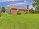 Green backyard featuring a well-kept lawn with a brick house and manicured landscaping at 1645 Woodview Ln, Anderson, IN 46011