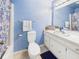 Bathroom with light blue walls, vanity with storage, toilet, and shower with blue and white curtain at 1645 Woodview Ln, Anderson, IN 46011