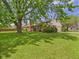 Charming brick home with large shade tree, grassy lawn, landscaping, attached garage, and chimney at 1645 Woodview Ln, Anderson, IN 46011