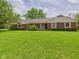 Ranch style home with brick and siding, a covered porch, and a large front yard with mature shade trees at 1645 Woodview Ln, Anderson, IN 46011