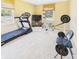 Brightly lit home gym with carpeted floor features treadmill, weights, exercise bike, and television at 1645 Woodview Ln, Anderson, IN 46011