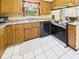 Well-lit kitchen featuring wood cabinetry, stainless steel appliances, white tile flooring, and updated fixtures at 1645 Woodview Ln, Anderson, IN 46011