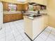 Functional kitchen layout with wood cabinets, white tile floors, and an island with cooktop at 1645 Woodview Ln, Anderson, IN 46011