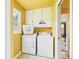 Laundry room with yellow walls featuring washer, dryer, cabinet, and view to living room at 1645 Woodview Ln, Anderson, IN 46011