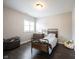 Cozy bedroom with a metal frame bed, wooden dresser, plush ottoman, and ample natural light from the window at 1648 Rossmay Dr, Westfield, IN 46074