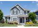 Charming two-story home featuring a covered porch, gray siding, stone accents, and professional landscaping at 1648 Rossmay Dr, Westfield, IN 46074