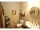 Cozy half bathroom with pedestal sink, toilet, decorative shelves, and framed artwork at 17003 Whitebark Ct, Westfield, IN 46074