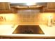Modern cooktop with a stylish range hood, set against a tiled backsplash, combining convenience with elegance at 17003 Whitebark Ct, Westfield, IN 46074