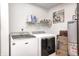 Well-equipped laundry room featuring modern white washer and dryer and convenient overhead shelving for storage at 1831 Whisperwood Trl, Danville, IN 46122