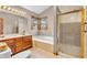 Well-lit bathroom with a soaking tub, double vanity sink, and a stand up shower with gold trim at 1934 Constitution St, Greenfield, IN 46140
