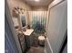 Well-lit bathroom with a vanity, mirror, storage, and a shower with a floral curtain at 209 N Lincoln St, Martinsville, IN 46151