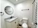 Bathroom featuring a shiplap wall, round mirror, and white vanity with stone top at 2431 Timbercrest Dr, Columbus, IN 47203