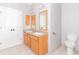 Bathroom with a wooden vanity, double mirrors, toilet, tile flooring, and white doors at 2761 Winding Creek Ln, Greenfield, IN 46140