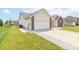 View of house showcasing the attached two-car garage, gravel accents, and well-manicured lawn at 2761 Winding Creek Ln, Greenfield, IN 46140