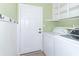 Well-lit laundry room with shelving, washer, dryer, hooks, and a white door at 2761 Winding Creek Ln, Greenfield, IN 46140