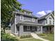 Charming two-story home with gray siding, white trim, a welcoming front porch, and well-manicured landscaping at 2940 N Park Ave, Indianapolis, IN 46205