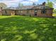 The back exterior of the brick home offers a lush lawn with a covered back porch at 3128 W 12Th St, Anderson, IN 46011