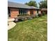 Lush front yard view of a brick home with mature trees, blue shutters, and manicured landscaping at 3128 W 12Th St, Anderson, IN 46011