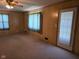 Sunlit living room with paneled walls, neutral carpet, large windows, and a glass door to the outdoor area at 3128 W 12Th St, Anderson, IN 46011