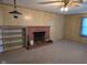 Comfortable living room showcasing a brick fireplace, built-in shelving, paneled walls, and vintage-style ceiling fan at 3128 W 12Th St, Anderson, IN 46011