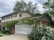 View of a two-car garage adorned with climbing plants and a tidy exterior surrounded by lush greenery at 3232 St Jude Dr, Indianapolis, IN 46227