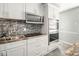Kitchen with stainless steel appliances, mosaic backsplash and white cabinets at 3846 Alsace Pl, Indianapolis, IN 46226