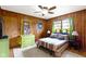 Warm bedroom with wood paneled walls, a cozy rug and a decorative ceiling fan at 5005 Bonnie Brae St, Indianapolis, IN 46228