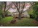 A cozy backyard with a wooden deck, a fire pit, mature trees, and a partially fenced yard at 5254 Kingsley Dr, Indianapolis, IN 46220