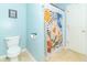 Bright bathroom with blue walls featuring a toilet and a patterned shower curtain at 5849 Wooden Branch Dr, Indianapolis, IN 46221