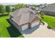 Birds eye view of a brick home with an attached three car garage, driveway and manicured lawn at 6077 W David Wayne Dr, New Palestine, IN 46163