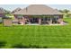 Expansive backyard with lush green grass and brick home with a covered patio is perfect for outdoor living at 6077 W David Wayne Dr, New Palestine, IN 46163