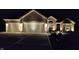 Charming brick home featuring a three-car garage and professional landscaping with outdoor lighting at night at 6077 W David Wayne Dr, New Palestine, IN 46163