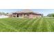 Landscaped backyard features a brick home with a covered patio, perfect for enjoying the outdoors at 6077 W David Wayne Dr, New Palestine, IN 46163