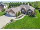 Aerial view of a well-maintained brick home with an attached three car garage and lush, green lawn at 6077 W David Wayne Dr, New Palestine, IN 46163