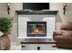 Close-up shot of the fireplace, with white bricks and decorative mantle. Comfortable seating is also present at 6096 E Conestoga Trl, Columbus, IN 47203