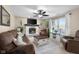 Bright living room featuring a painted fireplace, ceiling fan, large windows, and soft brown seating at 6096 E Conestoga Trl, Columbus, IN 47203