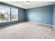 Bright bedroom featuring neutral carpet, blue accent wall, and double windows offering natural light and neighborhood views at 625 Streamside Dr, Greenfield, IN 46140